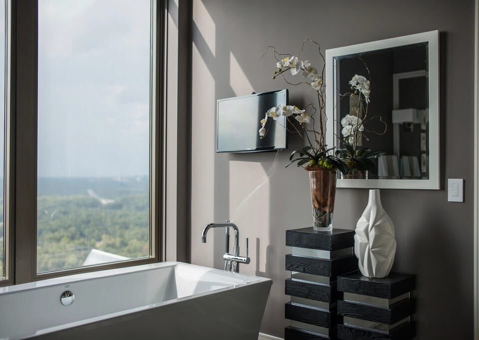 Freestanding tub beside a tall window looking over trees