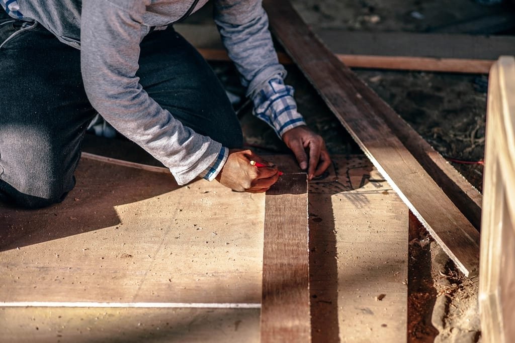 Craftsman fitting wood flooring by hand