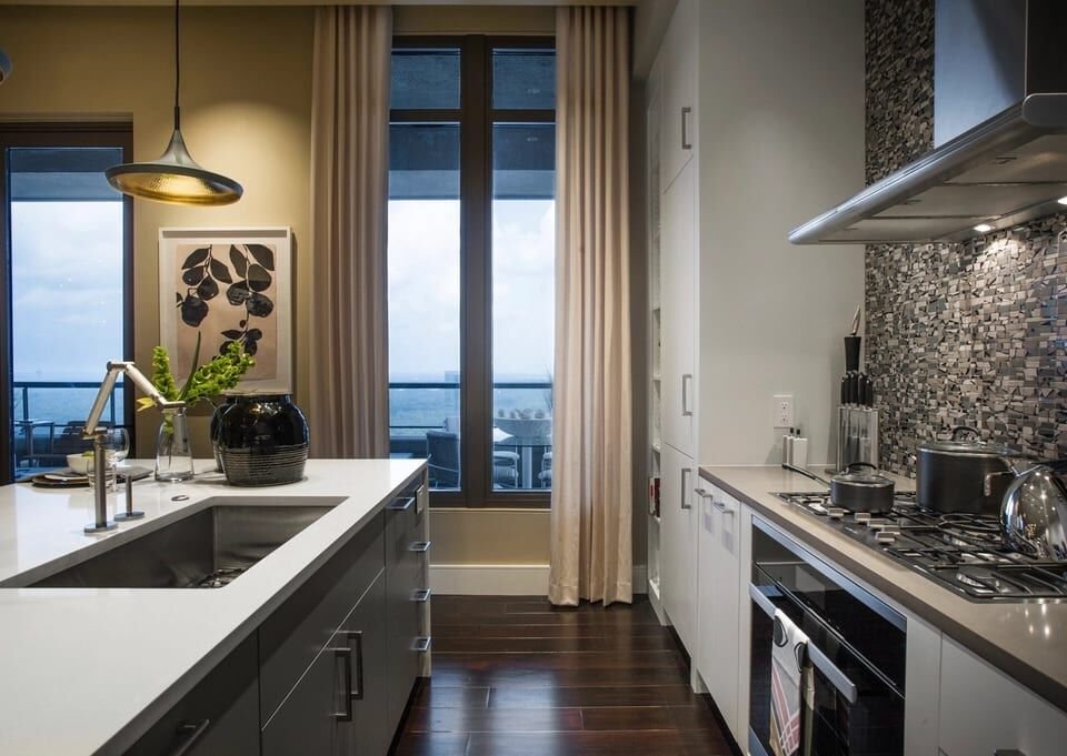 Dark, refined kitchen with stone counters and tall windows
