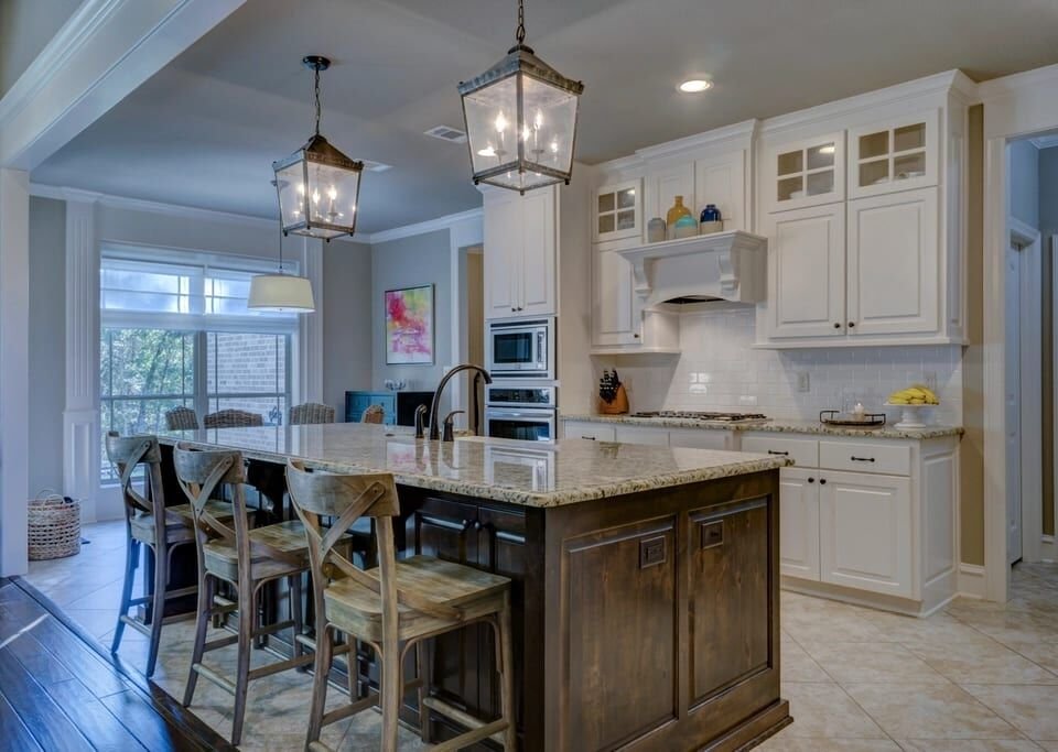 Bright kitchen with a large stone island and lantern pendants
