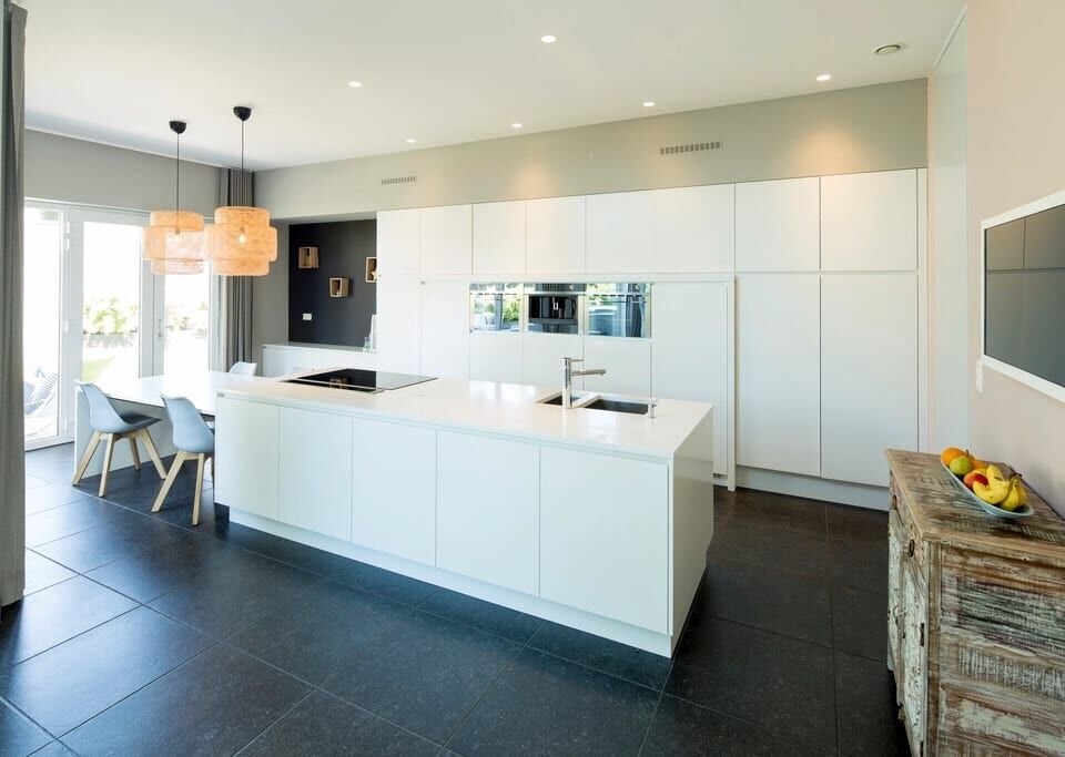 Minimal white kitchen with a long island and dark tile floor
