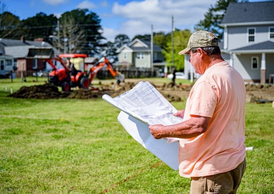 Builder reading plans on an empty lot