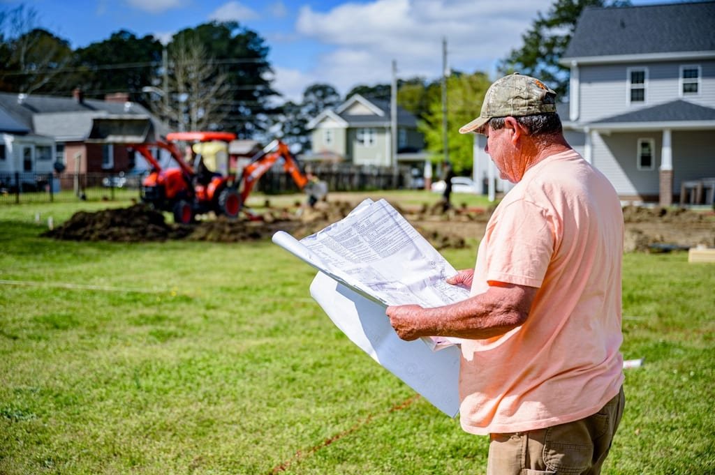 Builder reading plans on an empty lot
